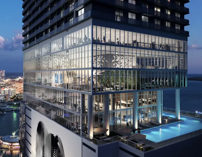 Modern high-rise with glass walls and a rooftop pool hosting Biohack Miami wellness events, overlooking the Miami skyline and waterfront at dusk